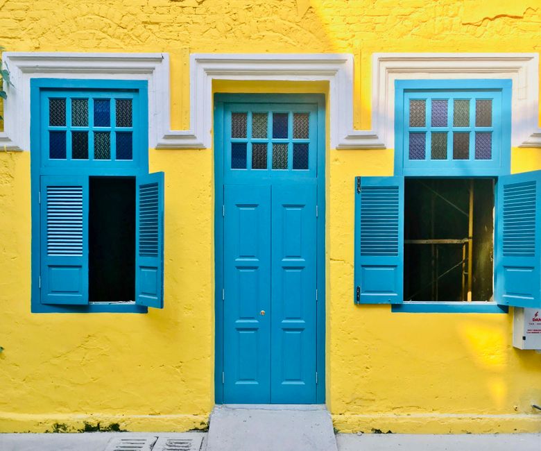 Yellow house front with a blue door and windows
