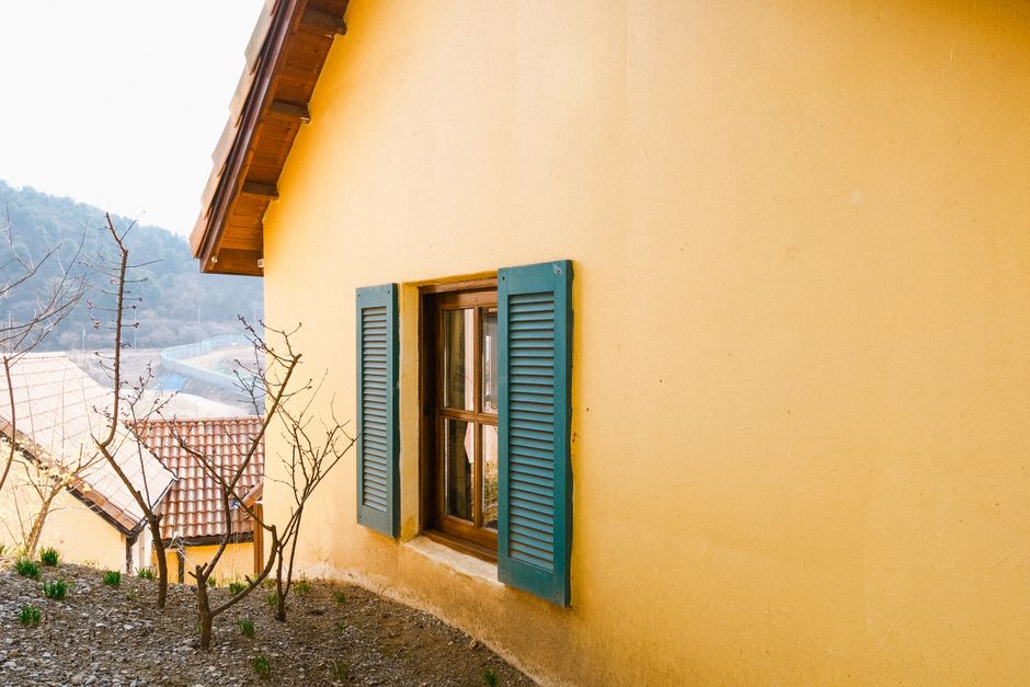 Yellow house wall with blue shutters