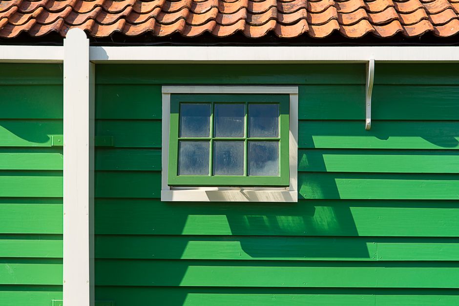 Green painted wall with a small window and a tile roof edge